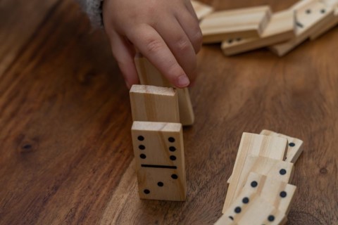 Child's hands in gray sweater playing dominoes with blurred focus