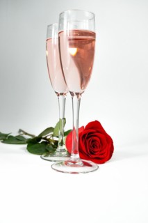 Two glasses of champagne and a rose on a white background and copy space valentine's day symbol