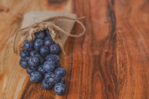 Fresh blueberries in a raffia bag on a wooden table