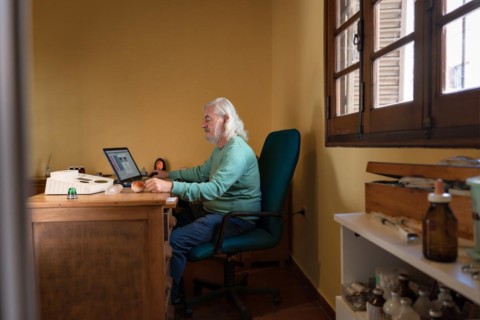 General shot of an elderly man sitting at his desk performing a quantum medicine analysis