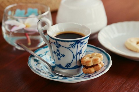 A shot of an espresso in an elegant ceramic demitasse with a biscuit at a cafe