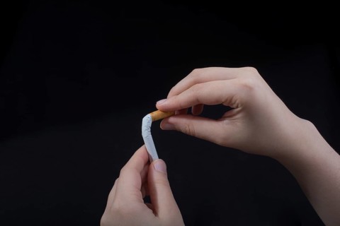Hand is breaking a cigarette on a black background
