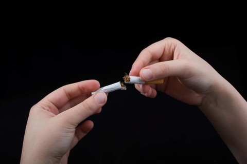 Hand is breaking a cigarette on a black background