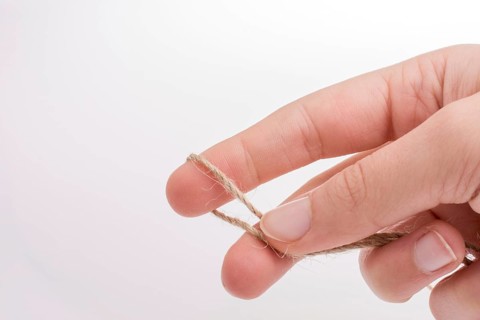 Hand holding linen thread on a white background