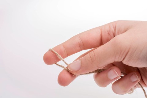 Hand holding linen thread on a white background