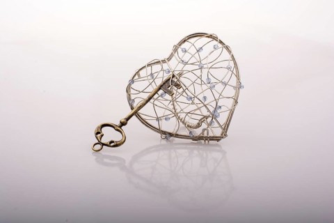 Key and a heart shaped metal cage on white