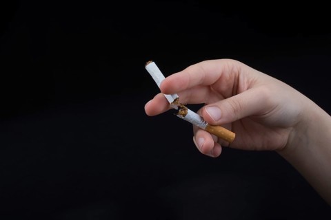 Hand is breaking a cigarette on a black background
