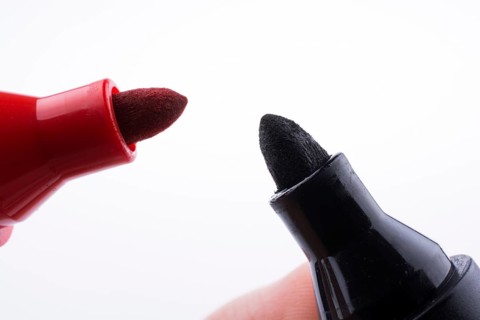 Hand holding Color markers face to face on a white background