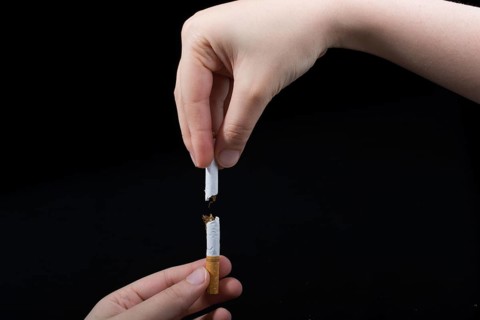 Hand is breaking a cigarette on a black background