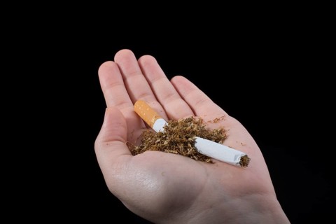 Hand is breaking a cigarette on a black background