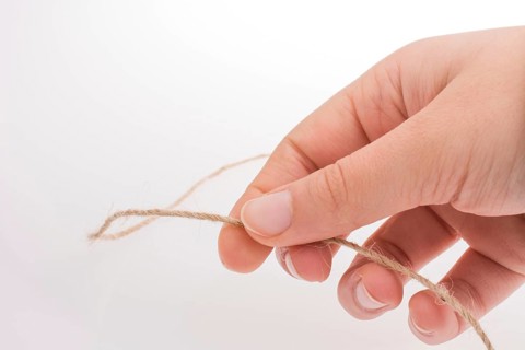 Hand holding linen thread on a white background