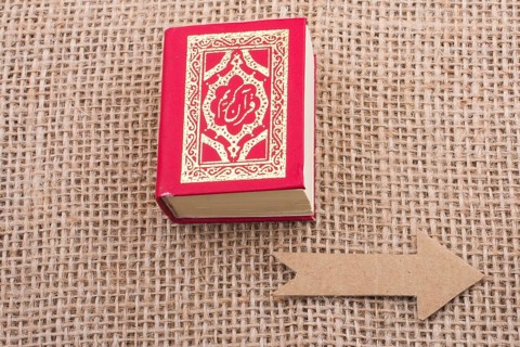 Paper arrow and Islamic Holy Book Quran in mini size