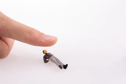 Hand threating to smash human figure on a white background
