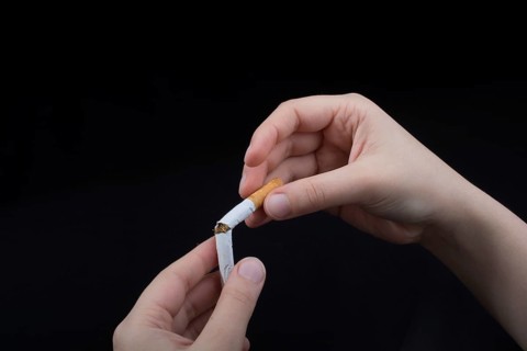 Hand is breaking a cigarette on a black background