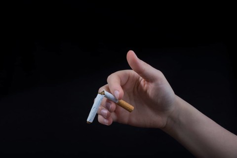 Hand is breaking a cigarette on a black background