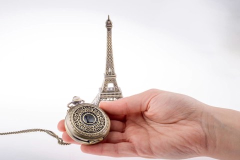 Hand holding a pocket watch befere Eifel Tower