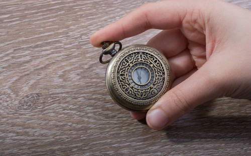 Retro style pocket watch in hand on black background