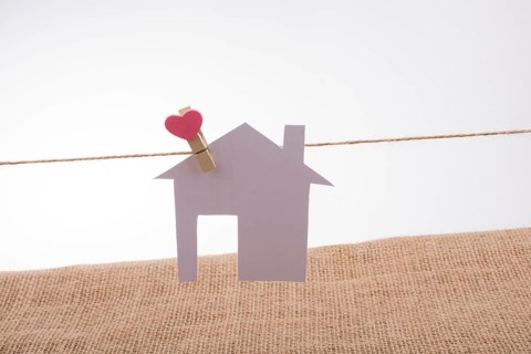 Little paper house attached to a string with a heart clip