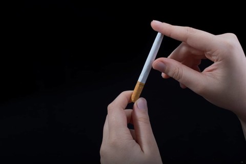 Hand is breaking a cigarette on a black background