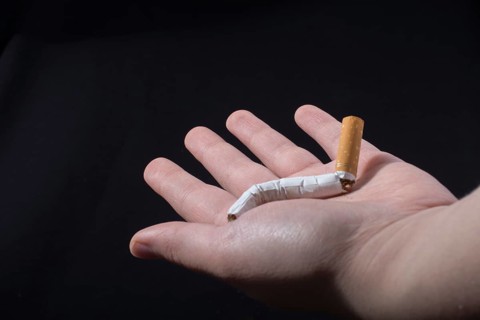 Hand is breaking a cigarette on a black background
