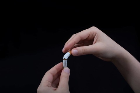 Hand is breaking a cigarette on a black background