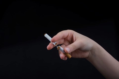 Hand is breaking a cigarette on a black background