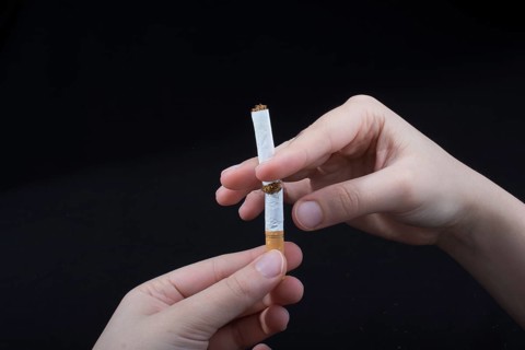 Hand is breaking a cigarette on a black background