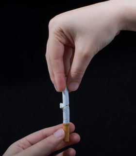 Hand is breaking a cigarette on a black background