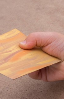 Hand holding painted note paper on brown background
