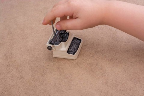 Hand holding a retro syled mini typewriter model