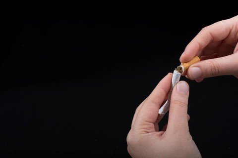Hand is breaking a cigarette on a black background