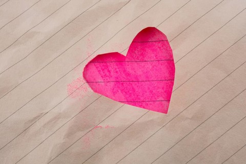 Hole made in lined paper on the form of a heart