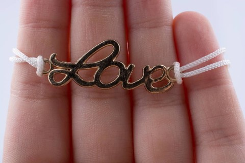 Love written with l letters made of metal in hand