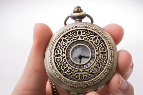 Retro style pocket watch in hand on white background