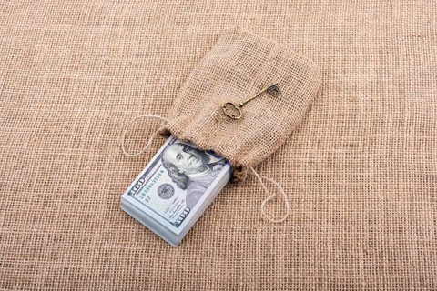 Retro key and bundle of US dollar in a sack on a canvas