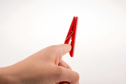 Hand holding a red clothespin on a white background