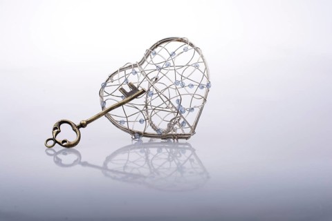 Key and a heart shaped metal cage on white