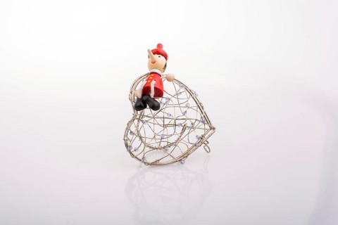 Wooden Pinocchio doll sitting on a heart shaped cage