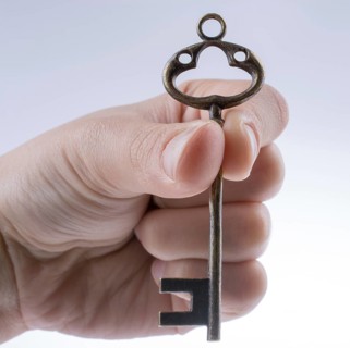 Hand holding a retro styled metal key on a white background