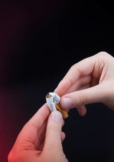 Hand is breaking a cigarette on a black background