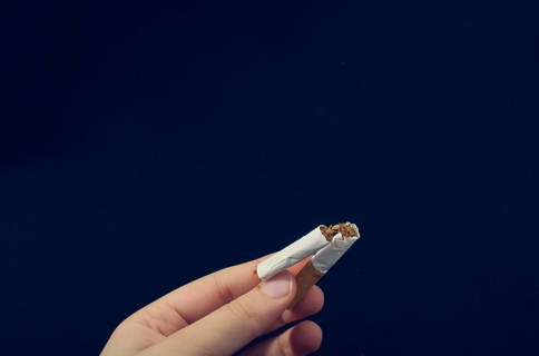Hand is breaking a cigarette on a black background