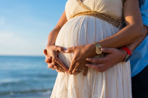 Pregnant maternity latin woman on the beach at sunset