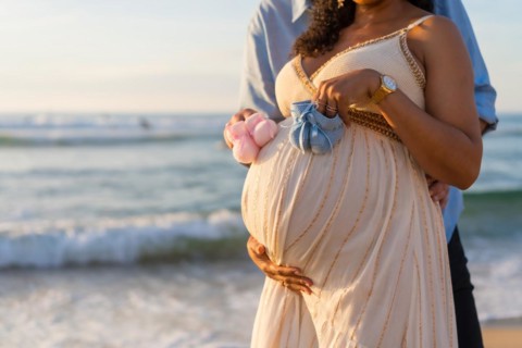 Pregnant maternity latin woman on the beach at sunset