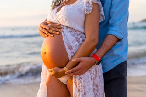 Pregnant maternity latin woman on the beach at sunset