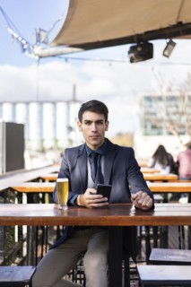 Businessman looking at camera e while holding his smartphone