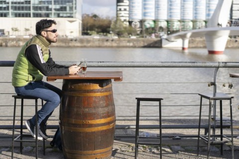 A pensive man looking away while sitting at a bar near the river
