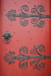 Red church door with fittings and decorations of the Romanesque St Ägidius Abbey Church