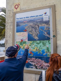 A man points to a map with the town of Porec in Istria on a house wall