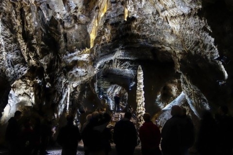 Tourists looking at big stalagmite during guided tour in the Caves of Han-sur-Lesse