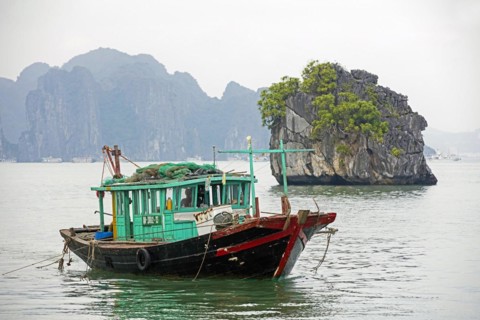 Wooden fishing boat and limestone monolithic islands in Ha Long Bay